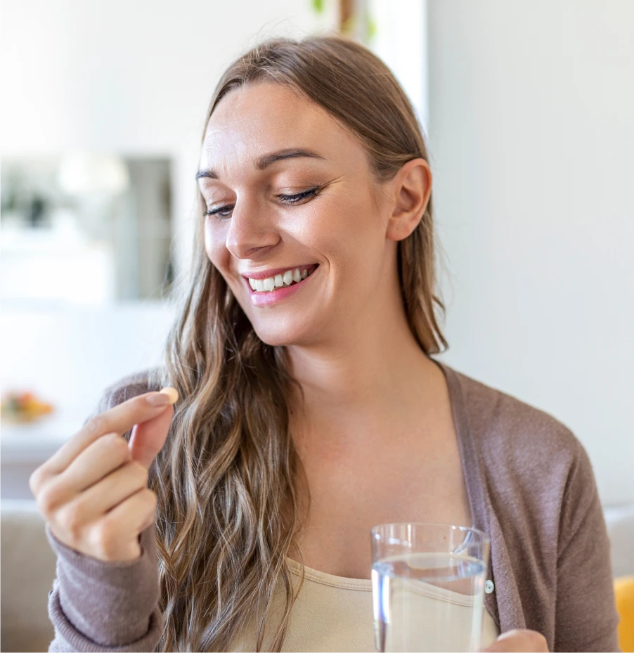 Smiling woman taking a pill with water – online psychiatry in Las Cruces, NM